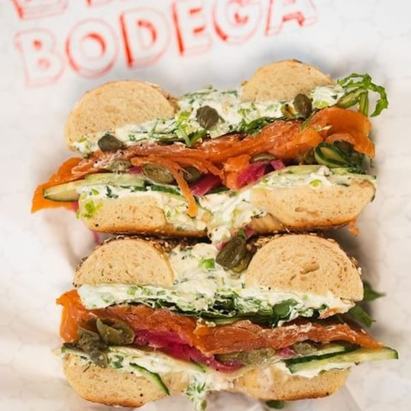 Two bagels with smoked salmon, cream cheese, capers, and cucumber on Big Bon Bodega paper.