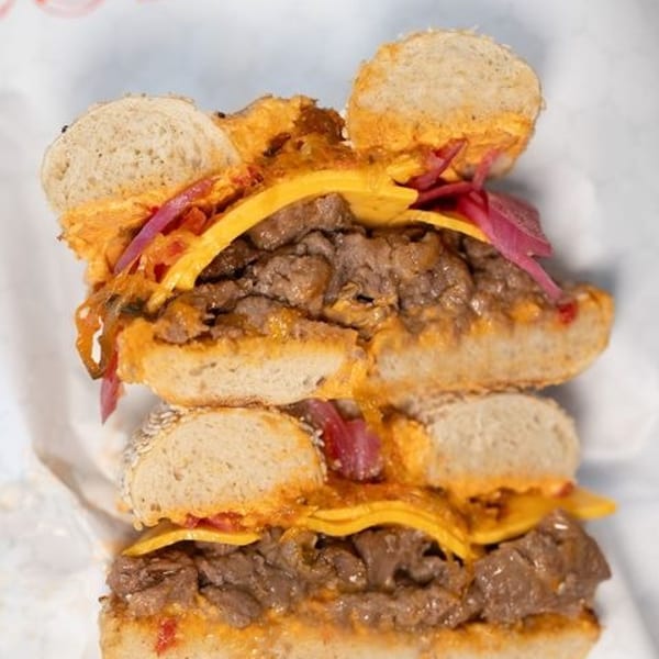 A Mickey Mouse-shaped bagel sandwich with steak, melted cheese, and pickled onions.